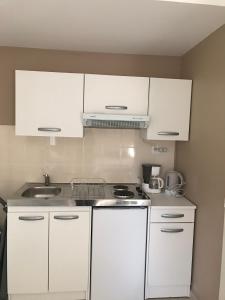 Una cocina blanca con gabinetes blancos y un fregadero. en Studio indépendant calme pas loin du centre, en Nimes