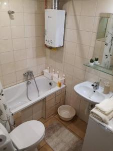a bathroom with a tub and a toilet and a sink at Kremerowska Apartment in Krakow