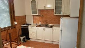 a kitchen with white cabinets and a sink and a refrigerator at Mária Villa in Balatonboglár