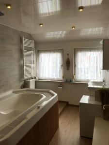 a large bathroom with a tub and two windows at Ferienwohnung mit Whirlpool in Ihlienworth