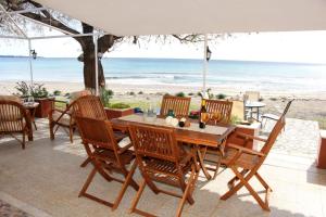 a wooden table and chairs on a patio with the beach at Marina Beach House in Lartos