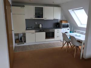 a kitchen with white cabinets and a table with chairs at Ferienwohnung mit Whirlpool in Ihlienworth
