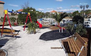 a park with a playground with benches and swings at Apartment Pradini in Poljana