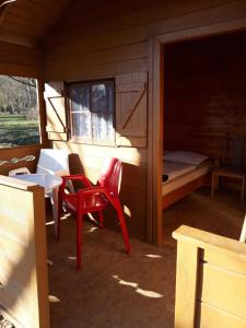 a small cabin with a red chair and a bed at Göcsej Völgye Kemping in Kustánszeg