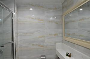 een badkamer met een douche, een wastafel en een spiegel bij LIC Plaza Hotel in Queens