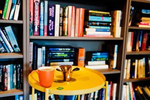 a yellow table with a cup on top of it in a book shelf at Smarthotel Forus in Stavanger