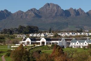 a large white house with mountains in the background at De Zalze Winelands Golf Lodge 6 in Stellenbosch