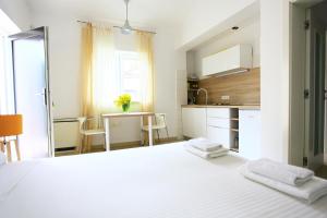 a white bedroom with a white bed and a kitchen at Apartmani Val in Pula