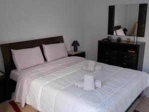ein Schlafzimmer mit einem weißen Bett und Handtüchern darauf in der Unterkunft *OI.KO HOUSE* City Apartments in Káto Achaḯa