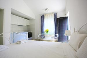 a white bedroom with a large bed and a table at Apartmani Val in Pula