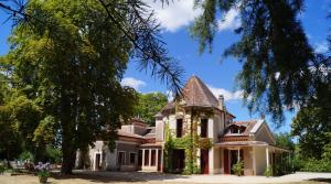 an old house with a turret and trees at Les Luz - Chambres d'hôtes in Uzeste
