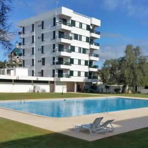 a swimming pool with two chairs in front of a building at Hello Sun in Vilamoura