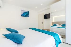 a bedroom with a white bed with blue pillows at KORČULA Antea Apartment in Prizba