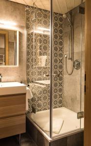 a bathroom with a tub and a sink and a shower at Das Nordberg Guesthouse in Garmisch-Partenkirchen