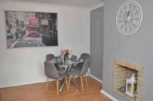 uma sala de jantar com mesa e cadeiras e um relógio em Croydon apartment with parking em Londres
