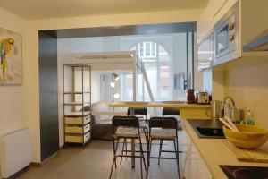 eine Küche mit einer Theke und Hockern in einem Zimmer in der Unterkunft Cosy Appartement proche Gares #1 in Lille