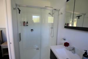 uma casa de banho branca com um chuveiro e um lavatório. em Brecon Pond Bed & Breakfast em Stratford