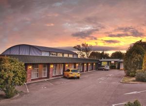 a building with a car parked in a parking lot at Palmerston North Motel in Palmerston North