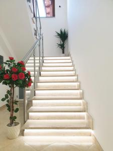 un escalier avec marches blanches et fleurs rouges dans l'établissement Pomodoro Bed, à Castrovillari