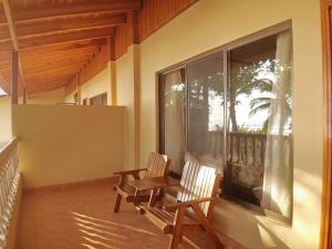 2 sillas de madera sentadas en un balcón con ventana en Hotel Delfin Playa Bejuco, en Esterillos Este