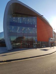 a large glass building with a red building at Slough Centre Townhouse with driveway parking for up to two cars in Slough