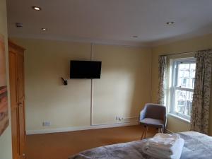 a bedroom with a bed and a television on the wall at Slough Centre Townhouse with driveway parking for up to two cars in Slough