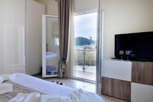 a bedroom with a bed and a television and a balcony at Katoi Apartment 2 Agios Georgios Pagoi in Agios Georgios Pagon