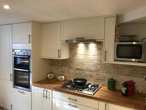 a kitchen with white cabinets and a stove top oven at 10 Grove St - Bath Holiday Suites in Bath
