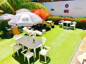 een tafel en stoelen en een parasol in de tuin bij Ótima Localização casa, 7 quartos-Porto de Galinhas 900m piscinas naturais in Porto De Galinhas