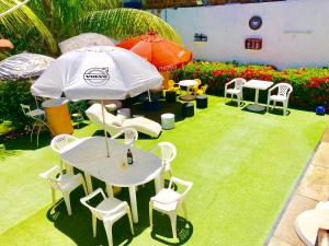 a table and chairs and an umbrella in a garden at Ótima Localização casa, 7 quartos-Porto de Galinhas 900m piscinas naturais in Porto De Galinhas