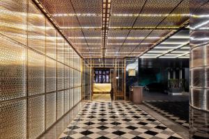 a hallway with a checkered floor and gold walls at Novotel Suites Sukhumvit 39 in Bangkok