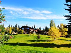 uma casa grande numa colina relvada com árvores em Northern Sky Lodge em Fairbanks