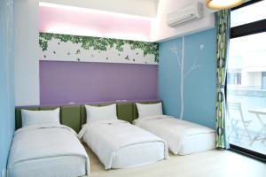Hualien KeyInn Space في مدينة هوالين: سريرين في غرفة مع لوحة على الحائط