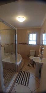 a bathroom with a tub and a toilet and a sink at Innikol 26 in Mossel Bay