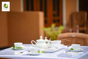 uma mesa com chávenas de chá e pires em Pine Trees Homestay em Nallathanniya