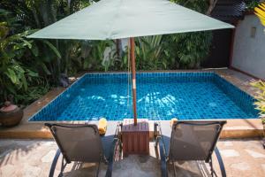 a swimming pool with two chairs and an umbrella at Pratumnak Soi 5 Bungalow 3 in Pattaya South