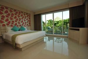 a bedroom with a bed and a television and a balcony at Chalong Beach Front Residence in Rawai Beach