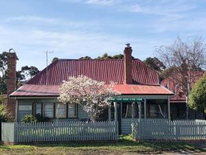a house with a red roof and a white fence at Kerrellie Cottages 2, 4 & 8 Reid Street in Strahan
