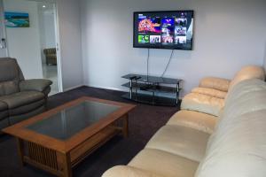 a living room with couches and a flat screen tv at Family Friendly Holiday Home in Mackay