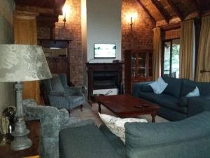 sala de estar con sofás azules y TV en Crocriver Chalet Schoemanskloof, en Schoemanskloof