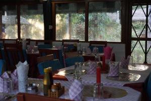 a dining room with tables and chairs and windows at Forest Hideaway Resort Pvt Ltd in Bhurkīā