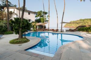 a swimming pool with tables and chairs next to the water at O Pescador an Indy Resort in Panaji
