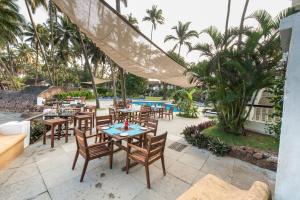 um pátio exterior com mesas e cadeiras e uma piscina em O Pescador an Indy Resort em Panaji