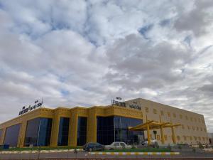 un gran edificio amarillo con un coche aparcado delante de él en Le Park Concord Hotel - Turaif, en Turaif