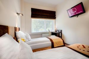 two beds in a room with a tv on the wall at Boutique Hotel's Sosnowiec in Sosnowiec