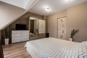 a bedroom with a bed and a dresser and a television at Apartment Doyran in Ruse