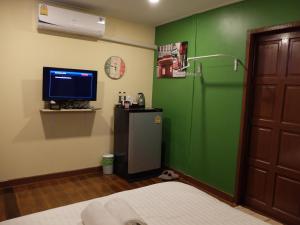 a room with a green wall and a television and a bed at Bed in Beyt Boutique Hotel in Nonthaburi