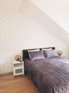 a bedroom with a bed and a white accent wall at Malūno Vilos apartamentai in Palanga