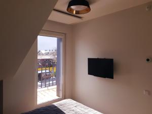 a bedroom with a flat screen tv and a window at Malūno Vilos apartamentai in Palanga