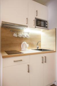 a white kitchen with a sink and a microwave at Dubingių apartamentai Nr. 2 in Vilnius